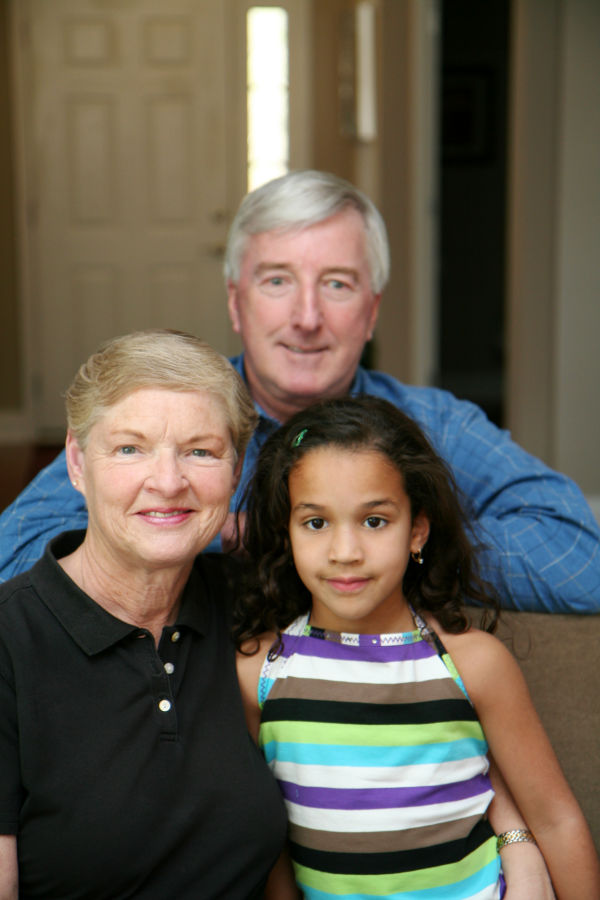 Senior couple together in their home with their granddaughter